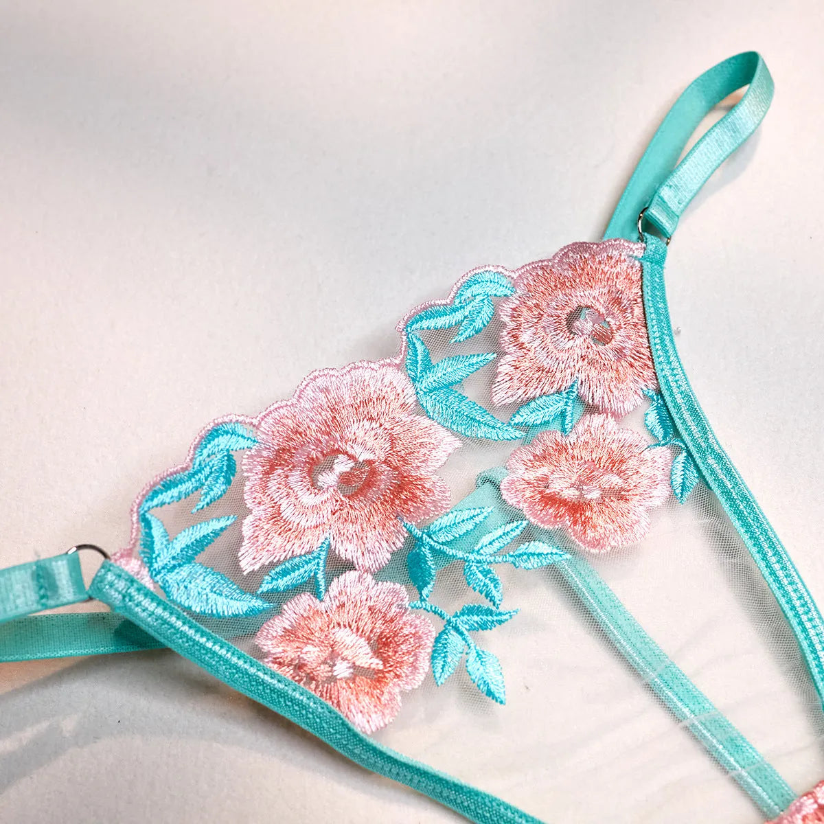 Pink embroidered women's bikini set with a matching mesh pettiskirt laid flat.