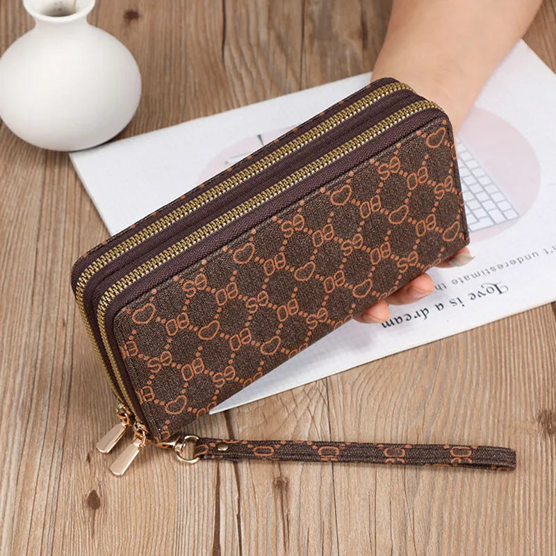 Black retro print long wallet clutch bag with zipper, holding a mobile phone and cards.