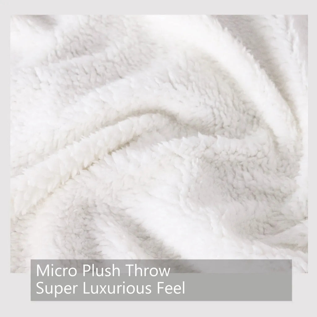 Dinosaur themed white sherpa fleece lamb wool blanket folded on a sofa
