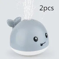 Whale-shaped electric bath toy spraying water with flashing lights, floating in baby bathtub