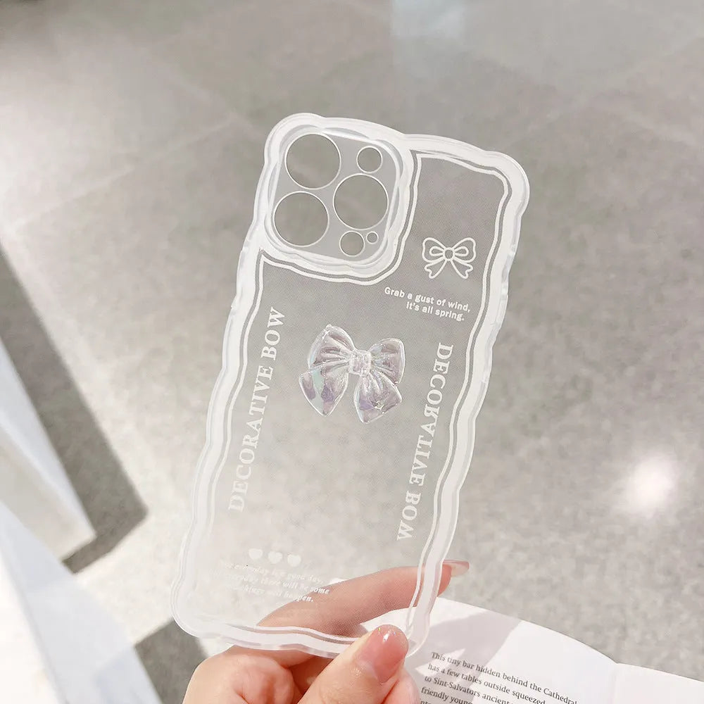 Clear iPhone case with a raised 3D transparent bow design on the back, shown with a white fabric lanyard.