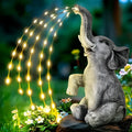 Resin elephant garden statue with built-in LED light strip on grass.