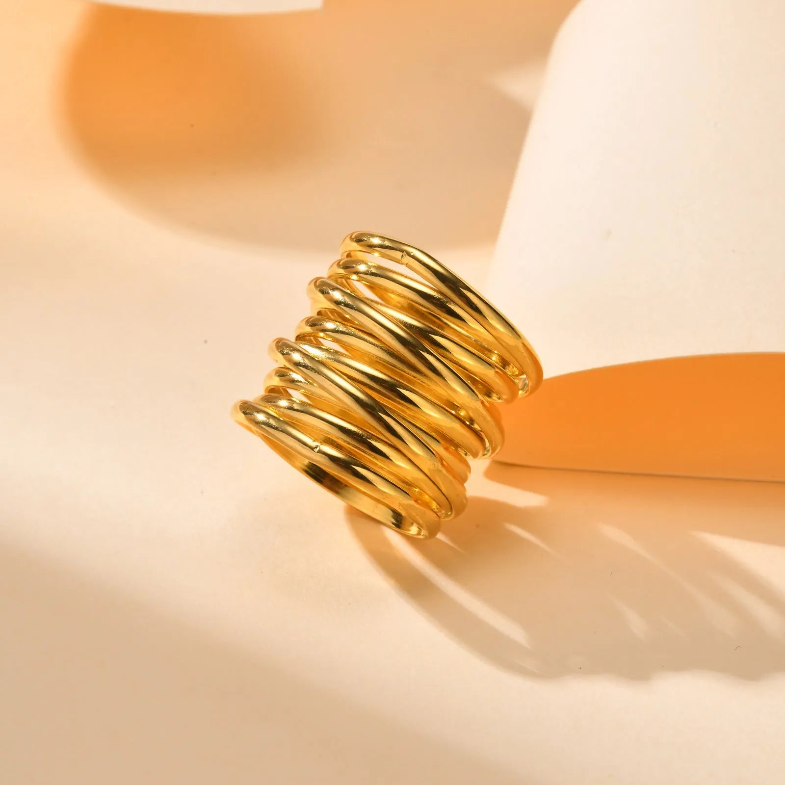 Gold electroplated stainless steel multi-loop multi-layer ring on white background in US size 7