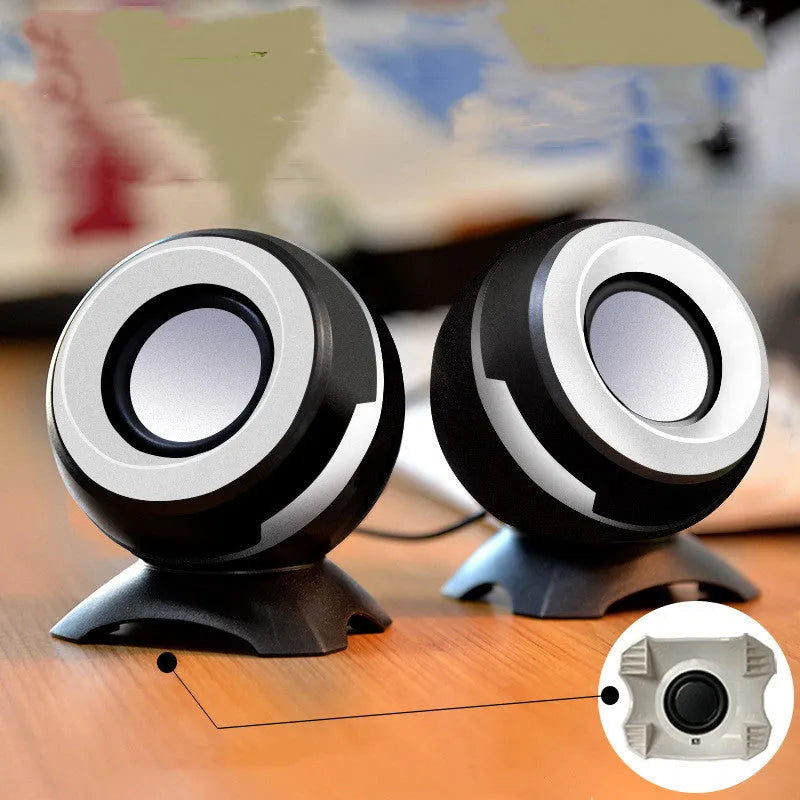 Compact black and gold USB-powered desktop speaker beside a laptop.
