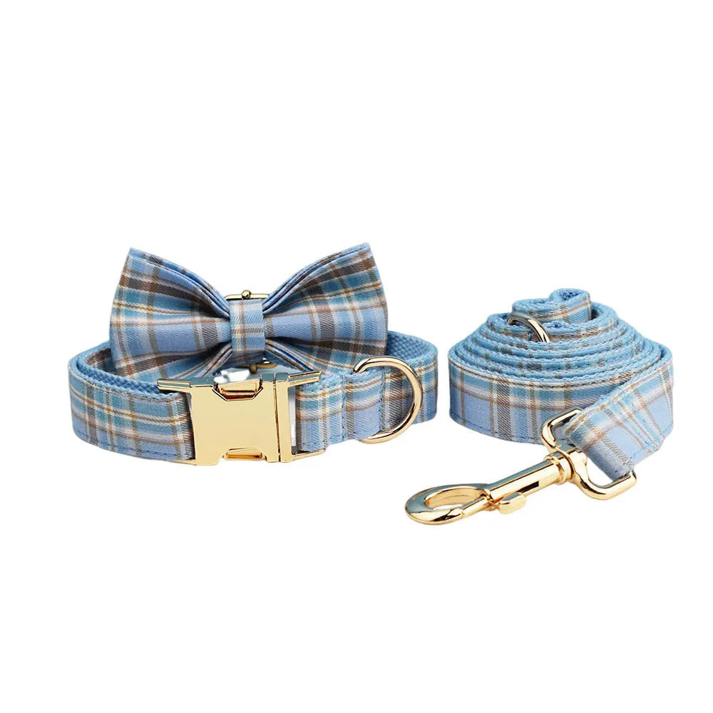 Sky blue grid forest pattern dog collar, leash, bow, and vest four-piece pet set laid out flat.