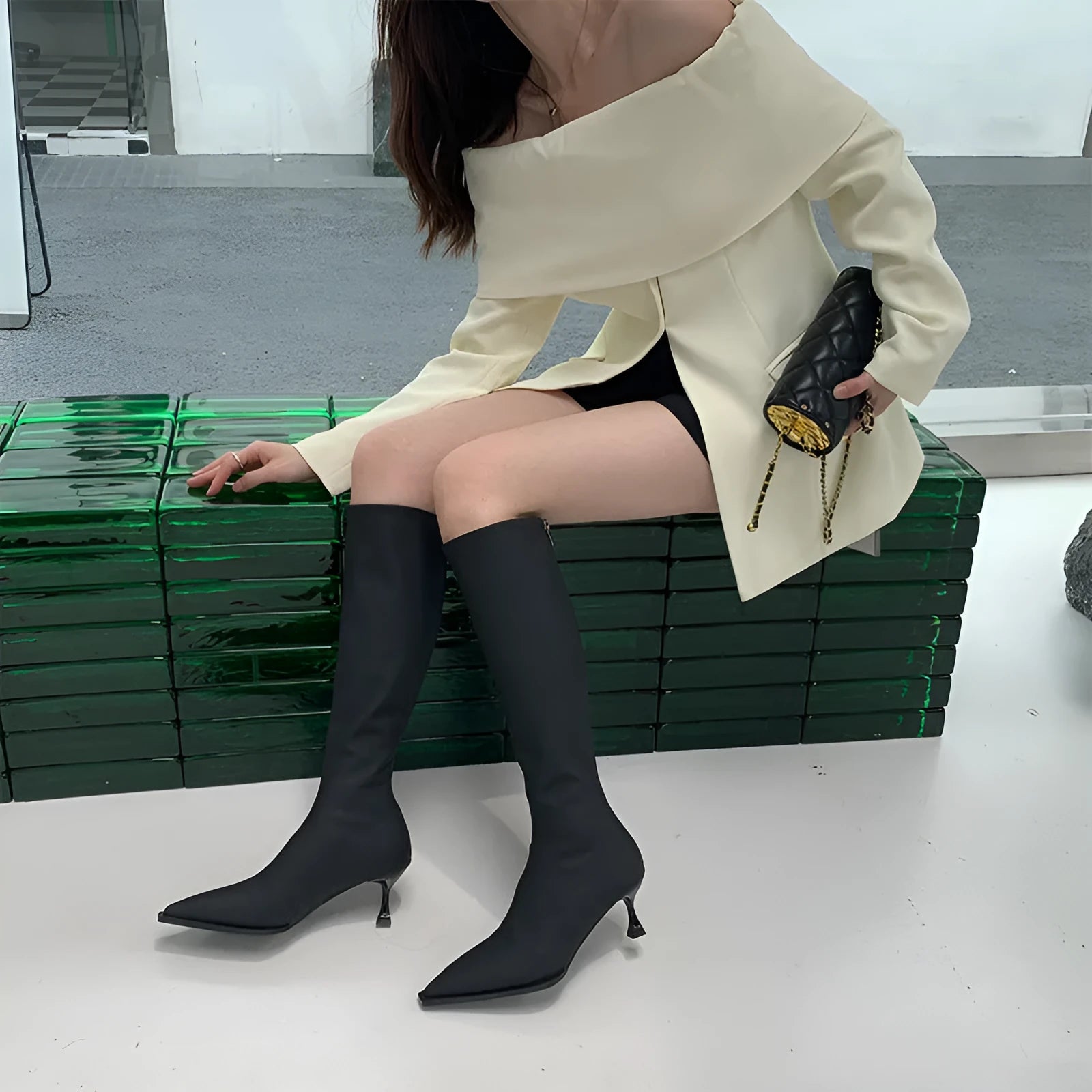 Women's black pointed toe stiletto heel boots with a back zipper, showing the below-the-knee shaft.