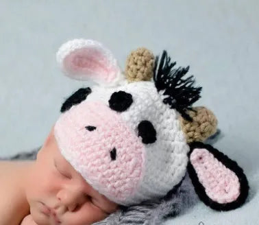 White hand-knitted baby cow suit set with matching hat and trousers for newborns.
