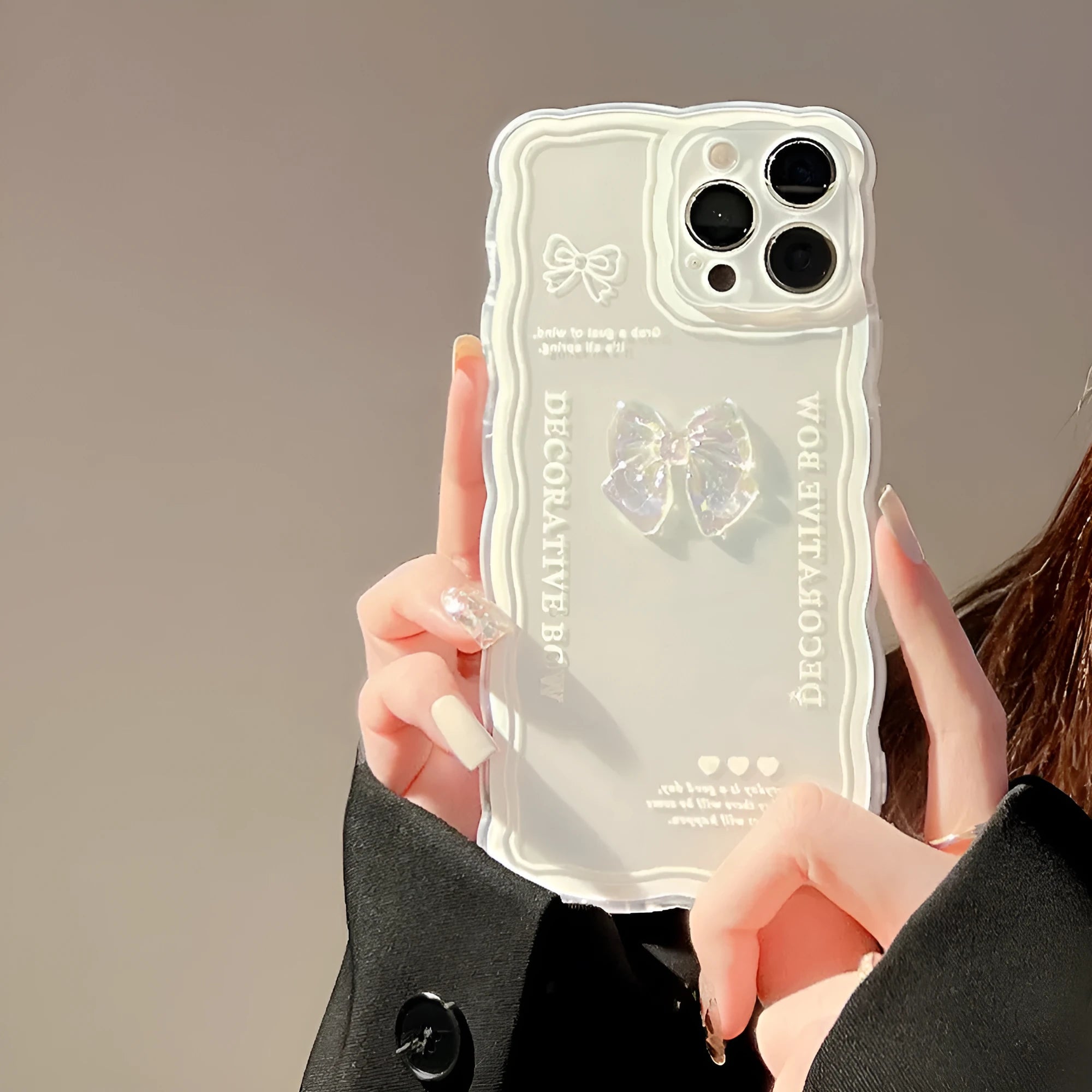 Clear iPhone case with a raised 3D transparent bow design on the back, shown with a white fabric lanyard.