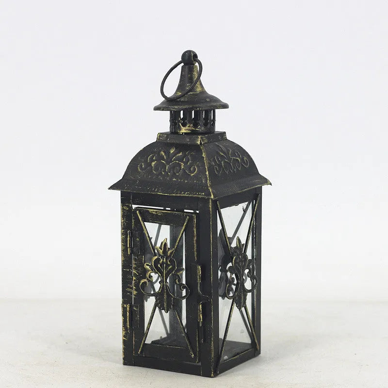 Black and white wrought iron floor standing storm lantern with tempered glass panels on a patio.
