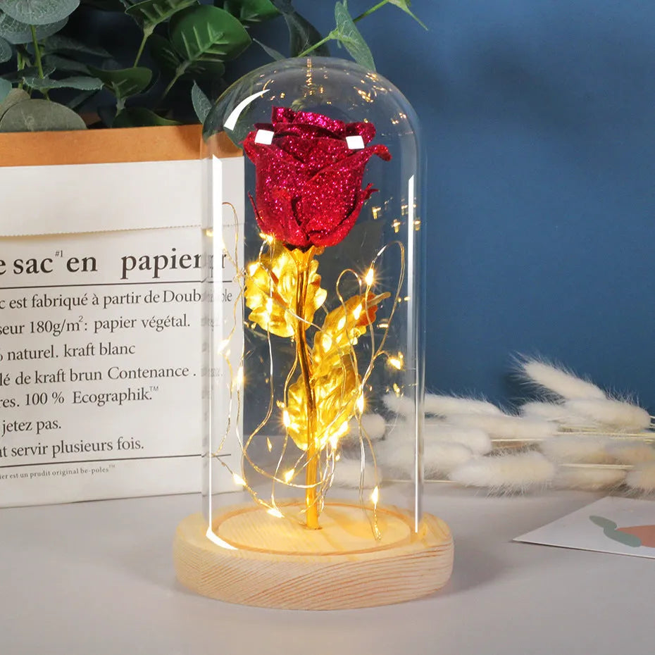 Glass dome containing red eternal roses illuminated by a warm white bendable LED light string.
