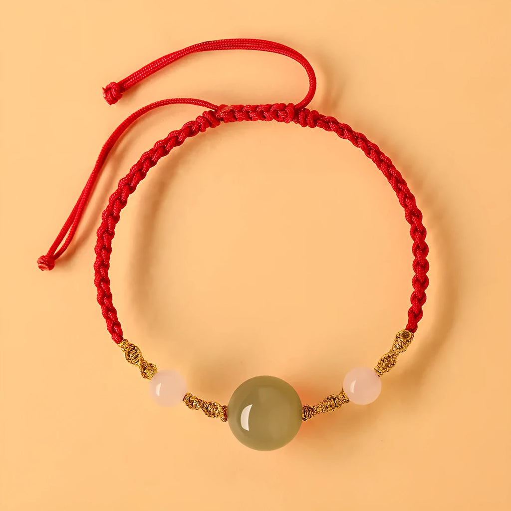 Hand-woven red rope bracelet with Hetian jade beads and intricate charm detailing.
