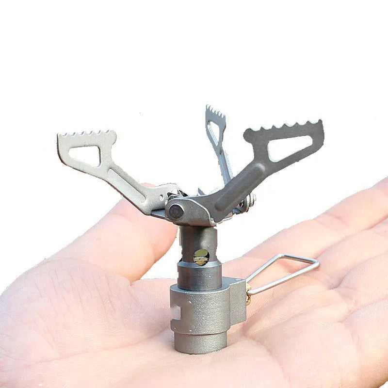 Portable metal propane camping stove with one-piece furnace design on a outdoor surface.