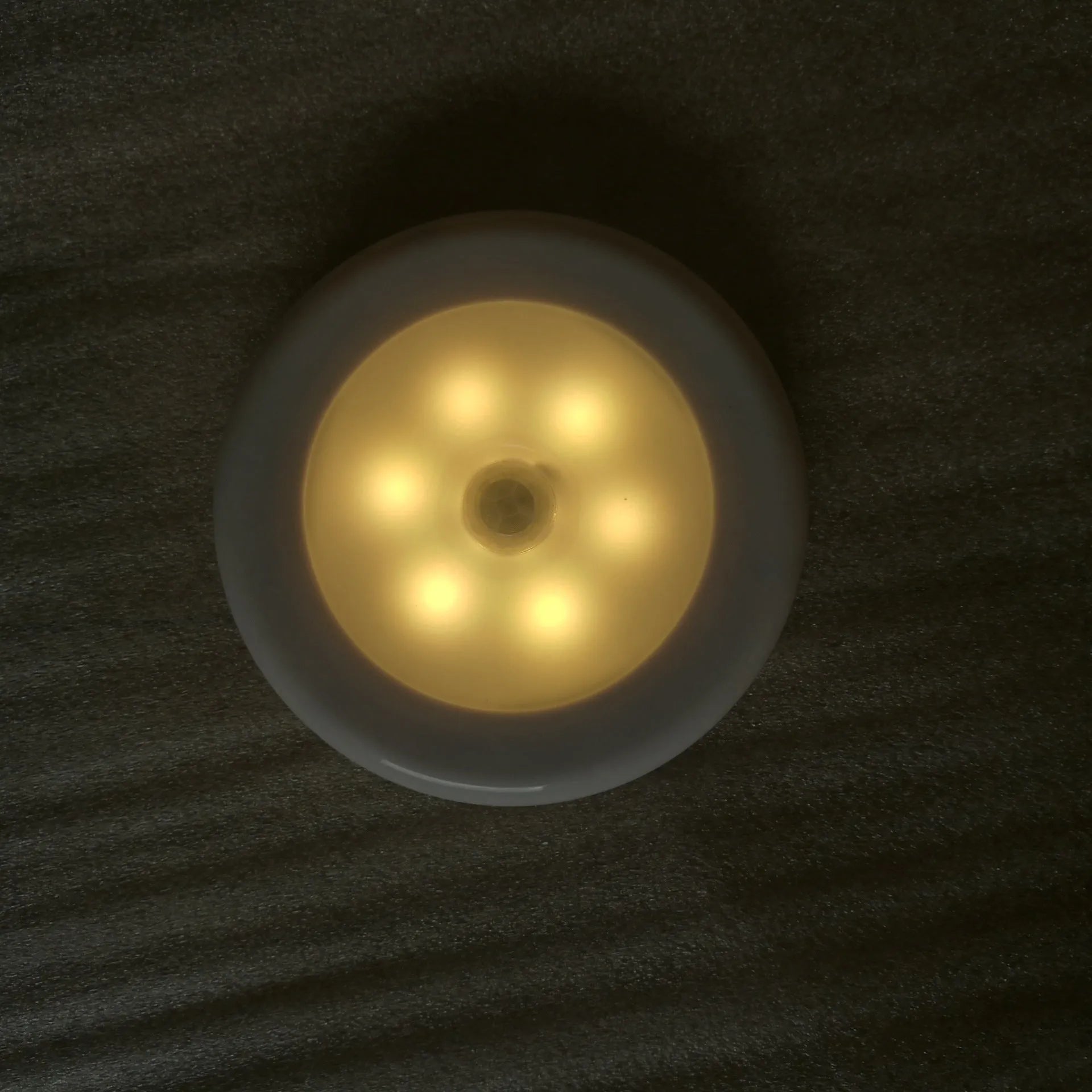 6LED motion sensor nightlight with strong magnet, white body, mounted on a ceiling corner, with motion detection arrows shown