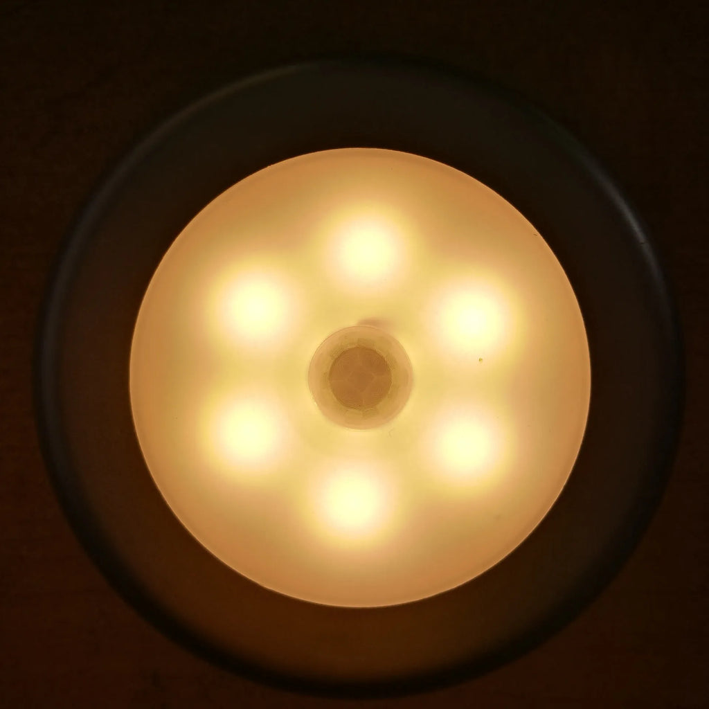 6LED motion sensor nightlight with strong magnet, white body, mounted on a ceiling corner, with motion detection arrows shown