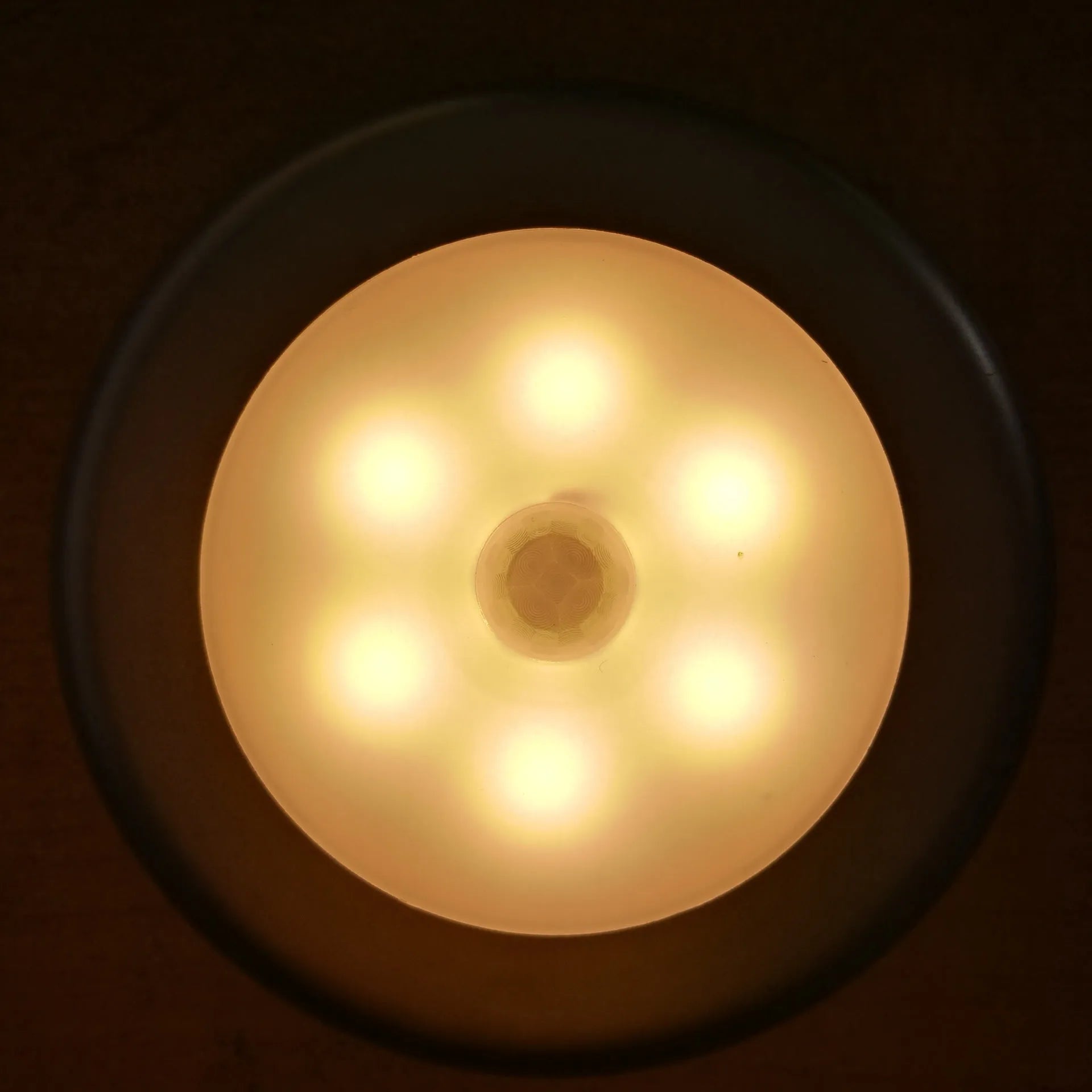 6LED motion sensor nightlight with strong magnet, white body, mounted on a ceiling corner, with motion detection arrows shown