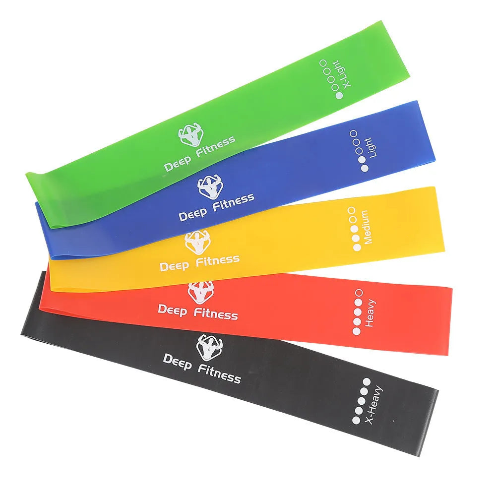 Yoga hip resistance band set in six colours from 0.4mm green to 1.2mm black laid flat on a surface