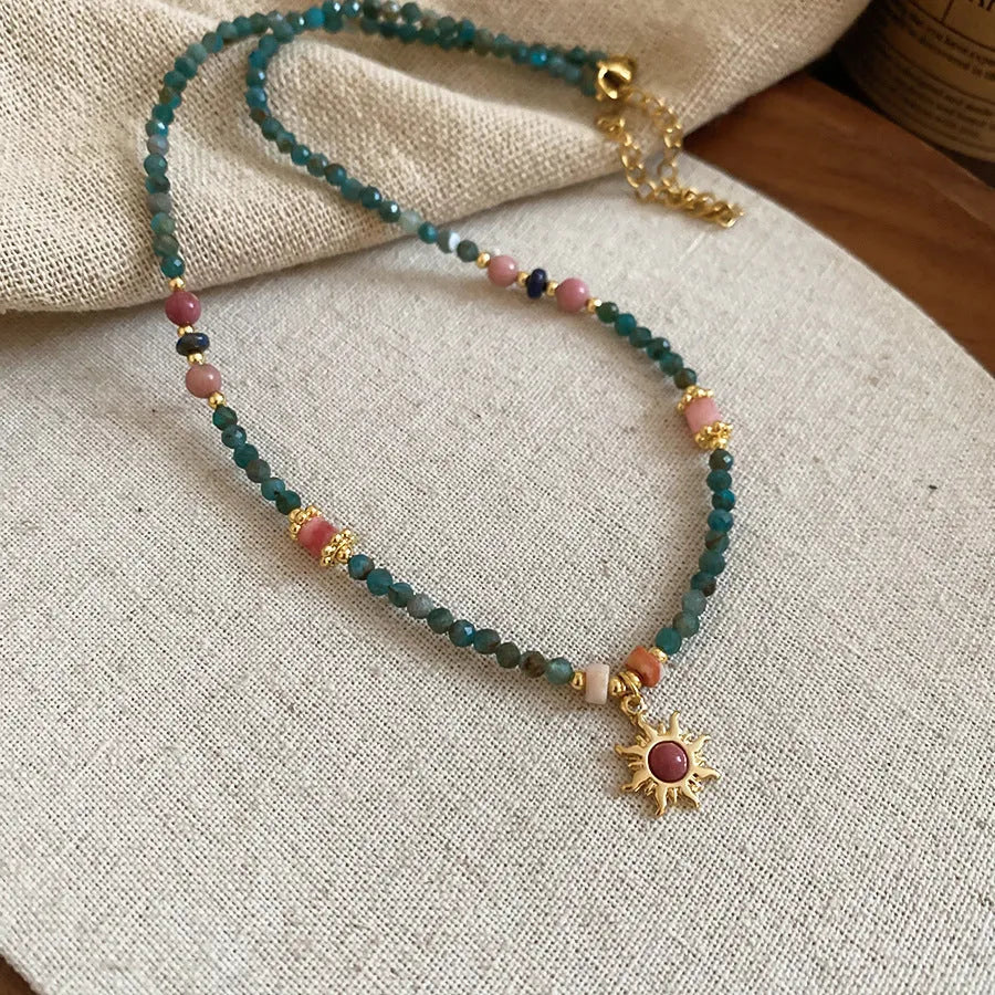 Freshwater pearl necklace with a blue stone sun pendant on an adjustable gold-toned chain.