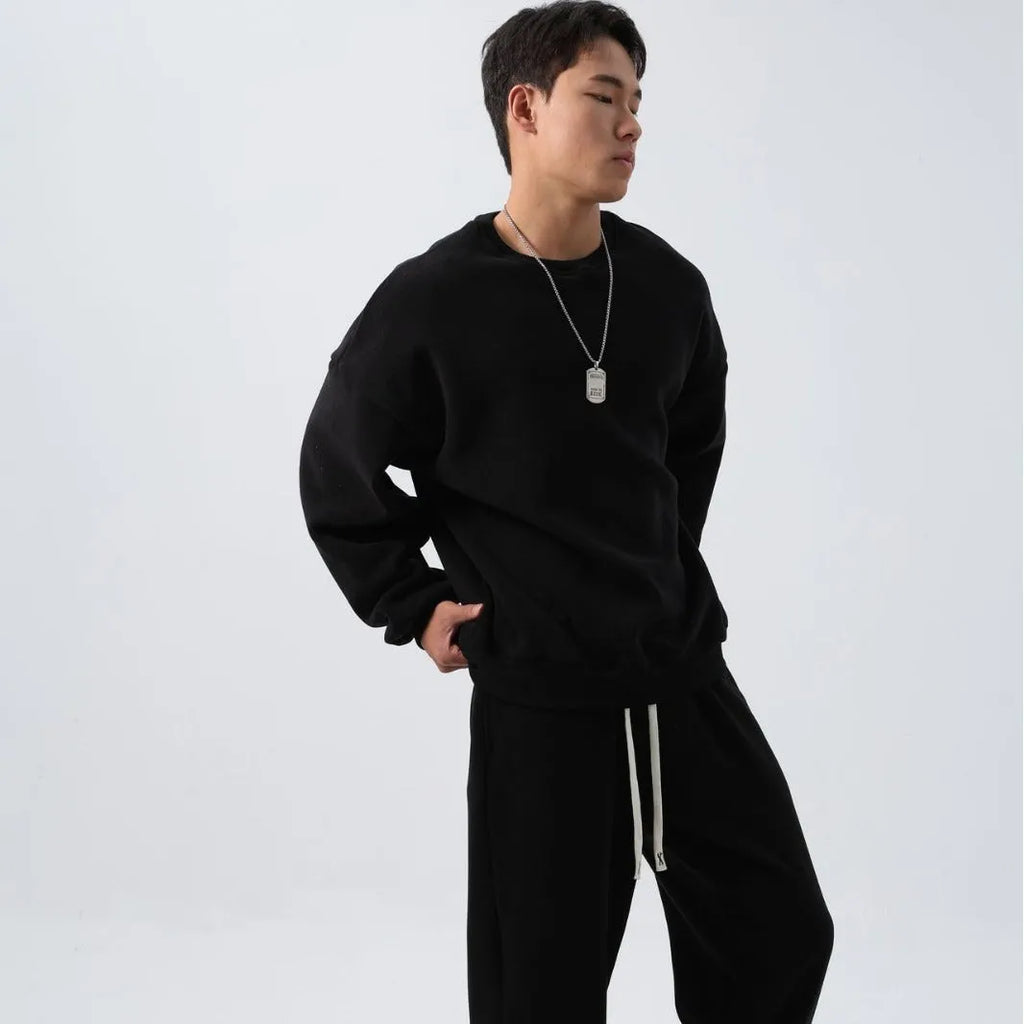 Men's black loose fit polar fleece winter sports suit with long sleeve coat and trousers on a hanger.