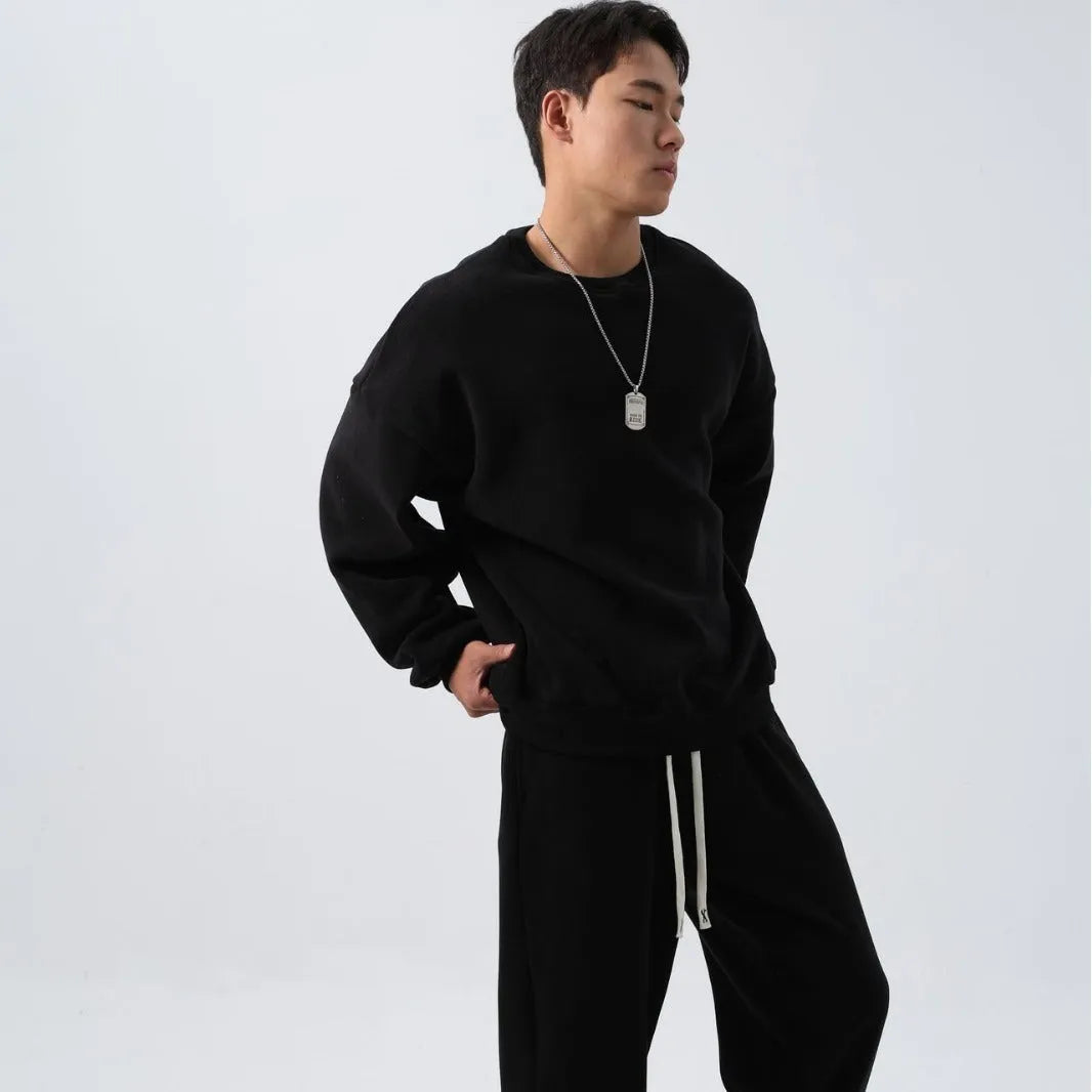 Men's black loose fit polar fleece winter sports suit with long sleeve coat and trousers on a hanger.
