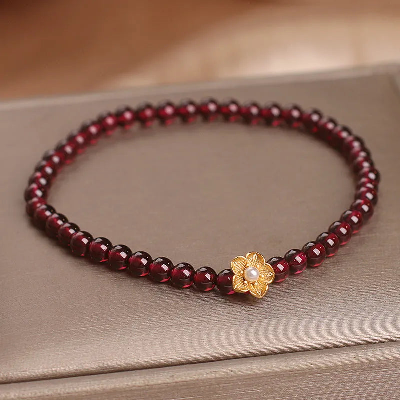 Red stone bead string bracelet with yellow flower accessories on wrist
