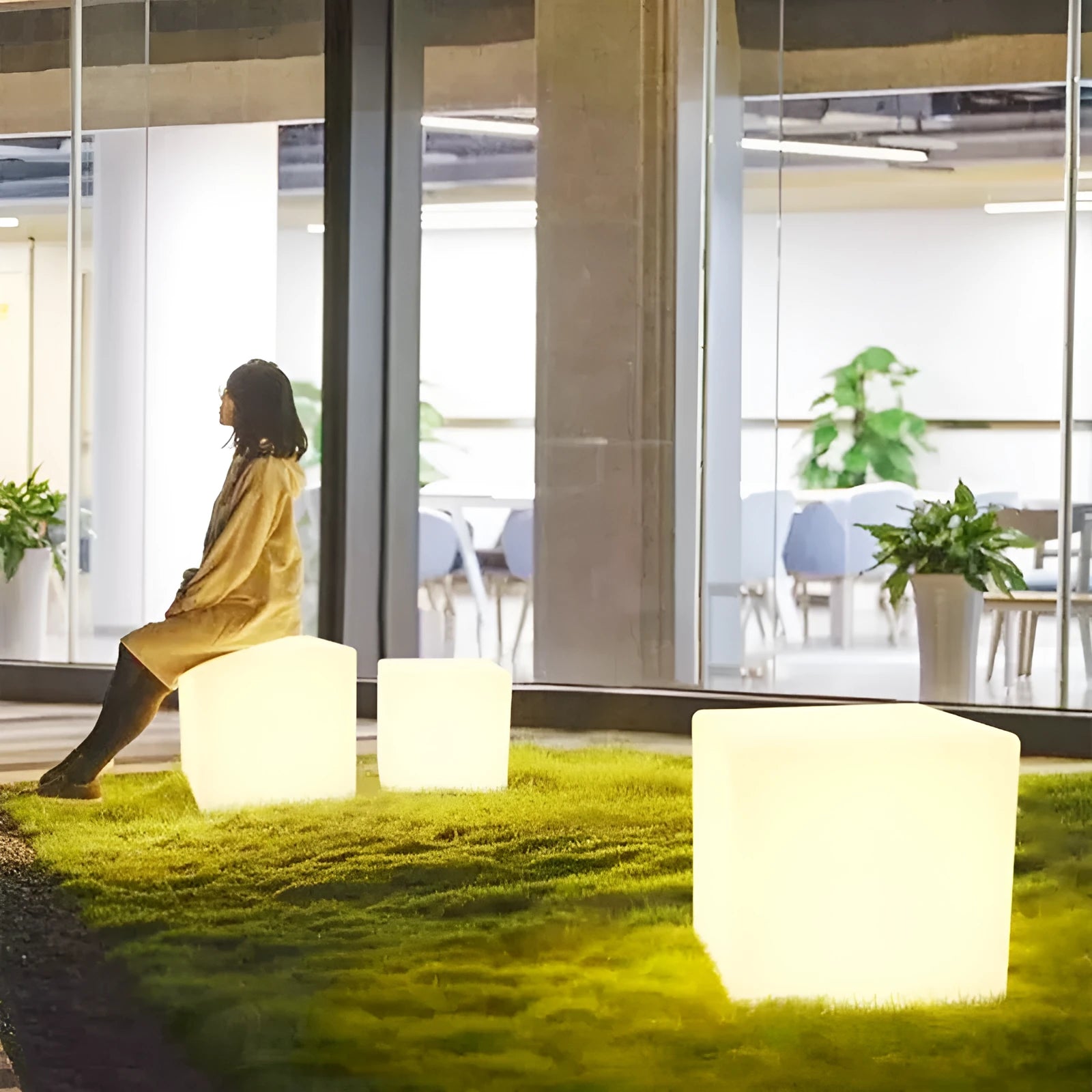 Modern square LED cube stool light outdoors, functioning as both a garden seat and a waterproof light source.