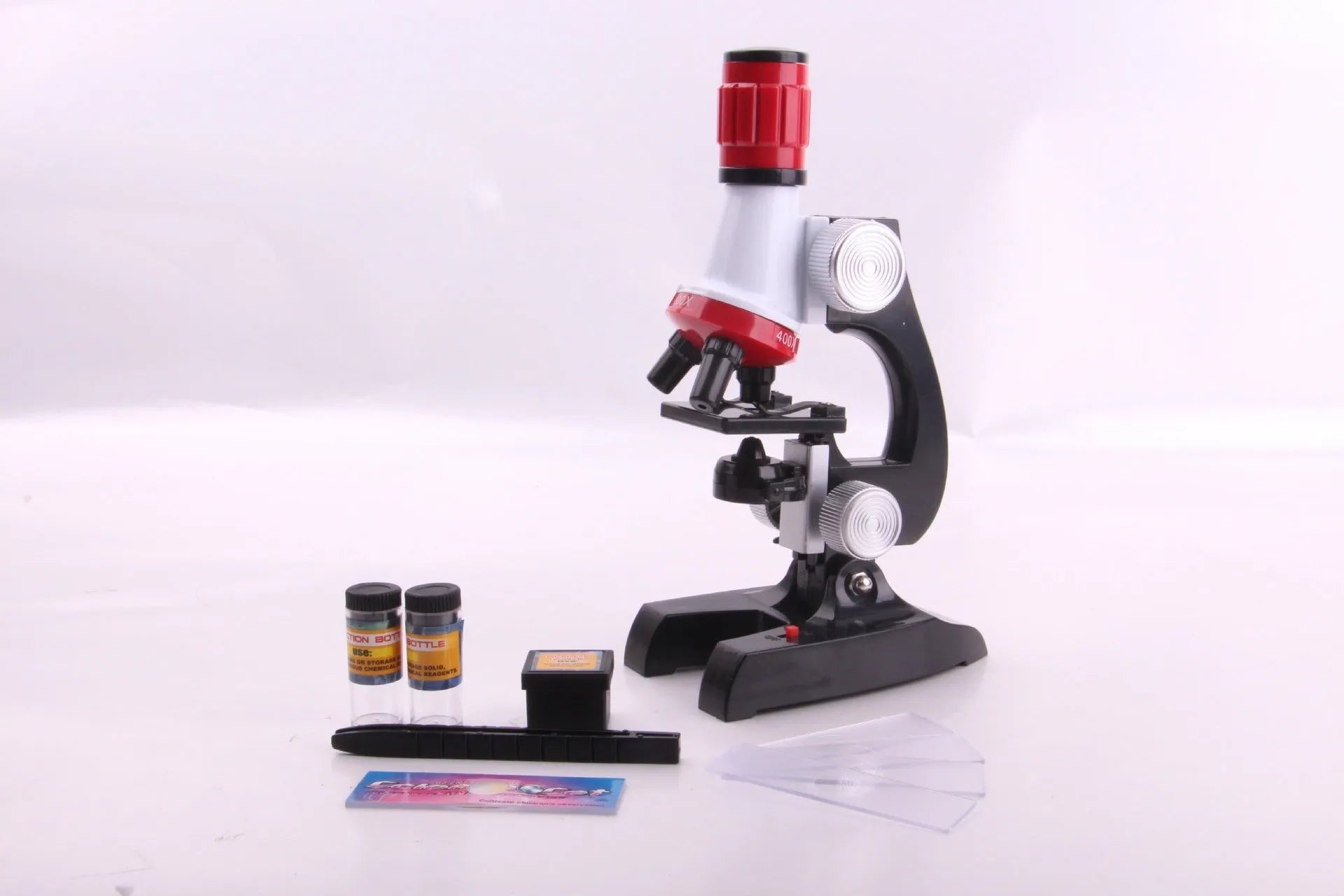 Child biological microscope with LED light, three objective lenses, and coarse focus knob on white background