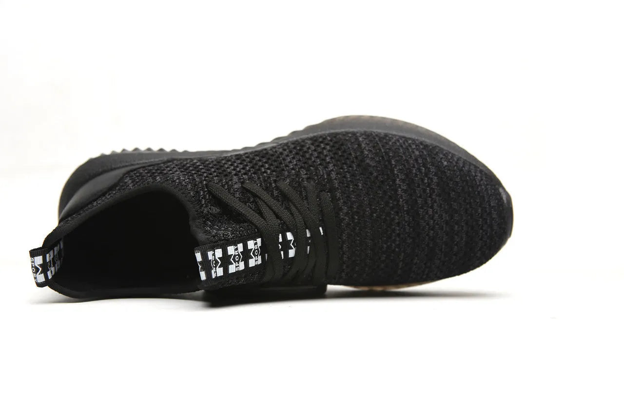 Men's black steel toe cap safety shoes with a low-cut design on a work surface.