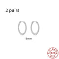 Close-up of twisted S925 sterling silver round ring earrings in gold colour on a plain background.