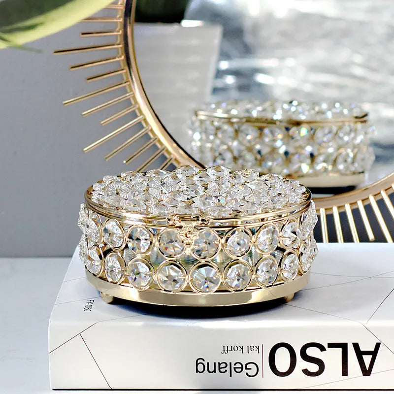 French gold iron jewelry storage box with a clear crystal glass lid on a wooden surface.