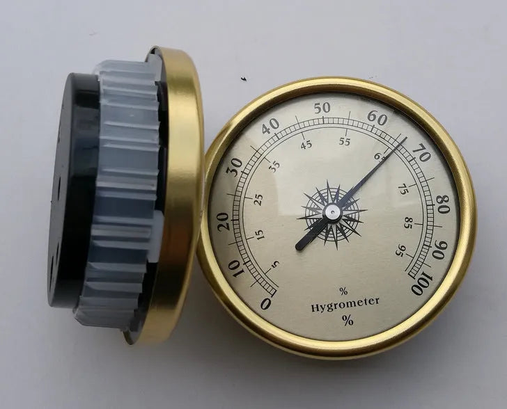 Analog thermometer and hygrometer with aluminium dial and outer ring on a white background.