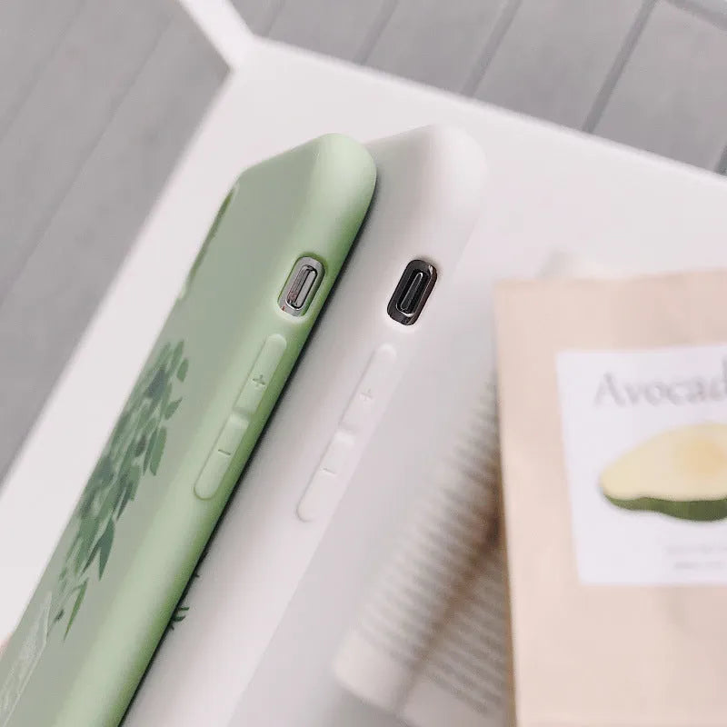 White silicone iPhone case with a painted green plant pattern on the back.
