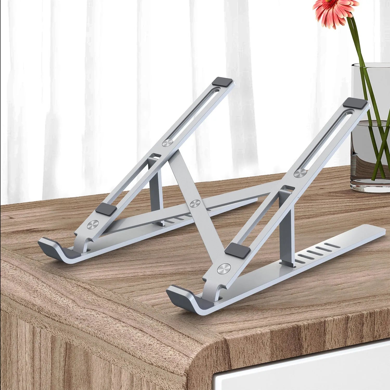 Silver aluminium laptop stand with six height positions beside a black laptop