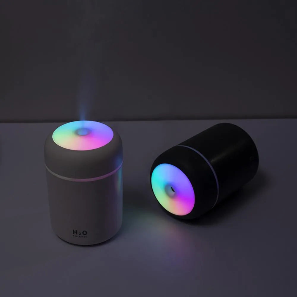 Pink, white, or navy blue USB mini desktop humidifier with atmosphere lights on a desk.