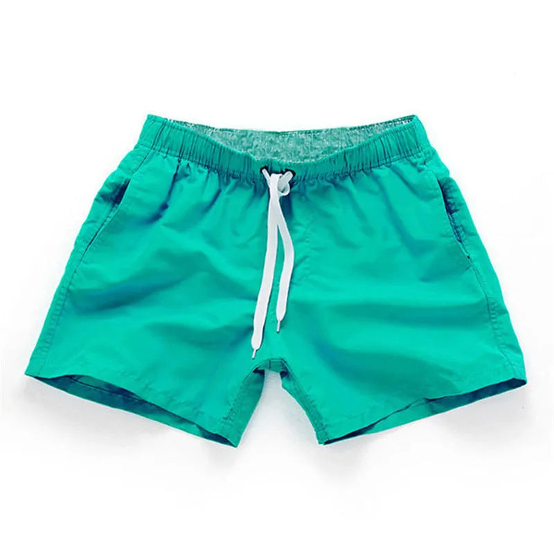 Men's straight-leg polyester surf shorts on a beach, available in multiple colours including fluorescent yellow and black.