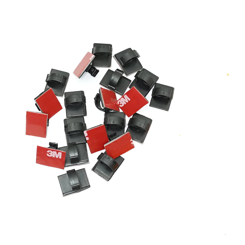 Black and white plastic self-adhesive cable clamps for car wire management on a clean surface.