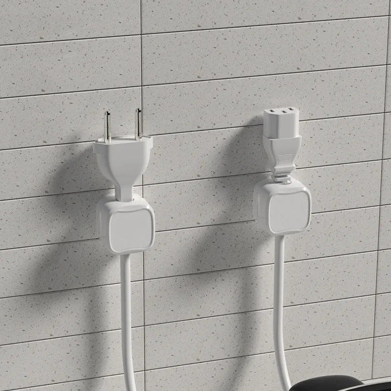 White and black magnetic cable clips holding a USB cable against a wooden desk edge.