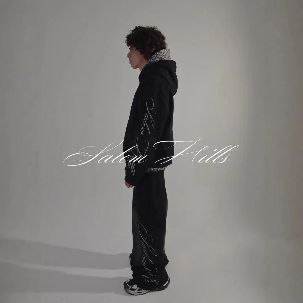 Men's black punk print pullover hoodie and matching trousers fleece-lined suit set laid flat.