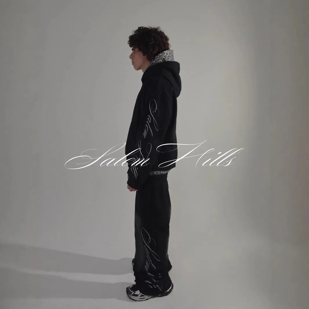 Men's black punk print pullover hoodie and matching trousers fleece-lined suit set laid flat.