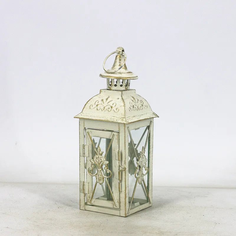 Black and white wrought iron floor standing storm lantern with tempered glass panels on a patio.