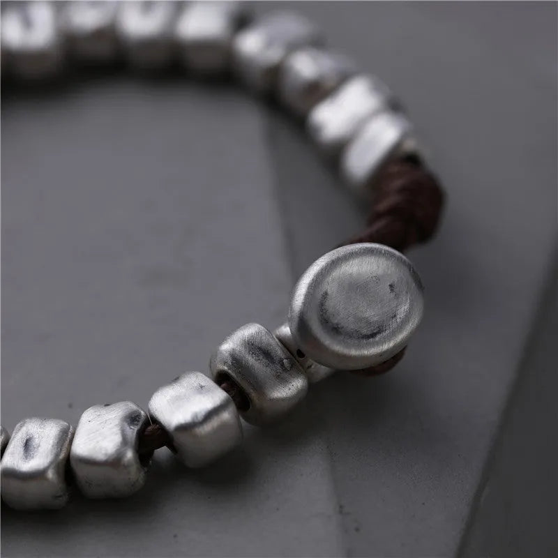 Handmade silver bracelet with an irregular square design and wooden details on an elasticated band.