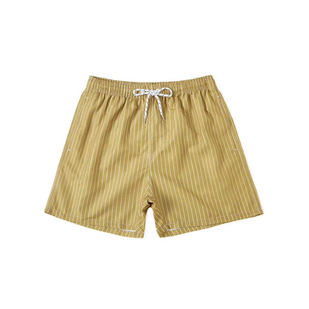 Man wearing navy blue and white striped straight-leg polyester beach shorts on shore.