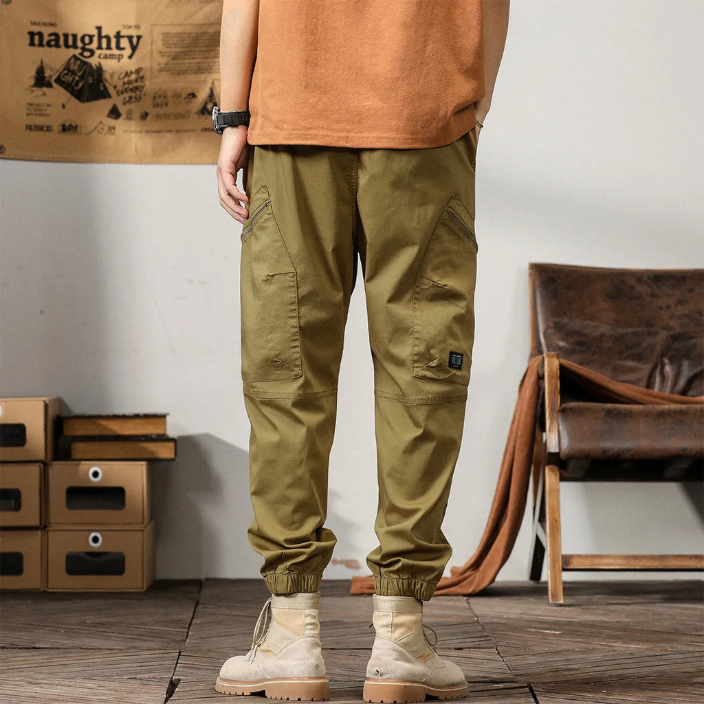 Man wearing khaki loose-fit cotton harem pants with tapered ankle-banded legs.