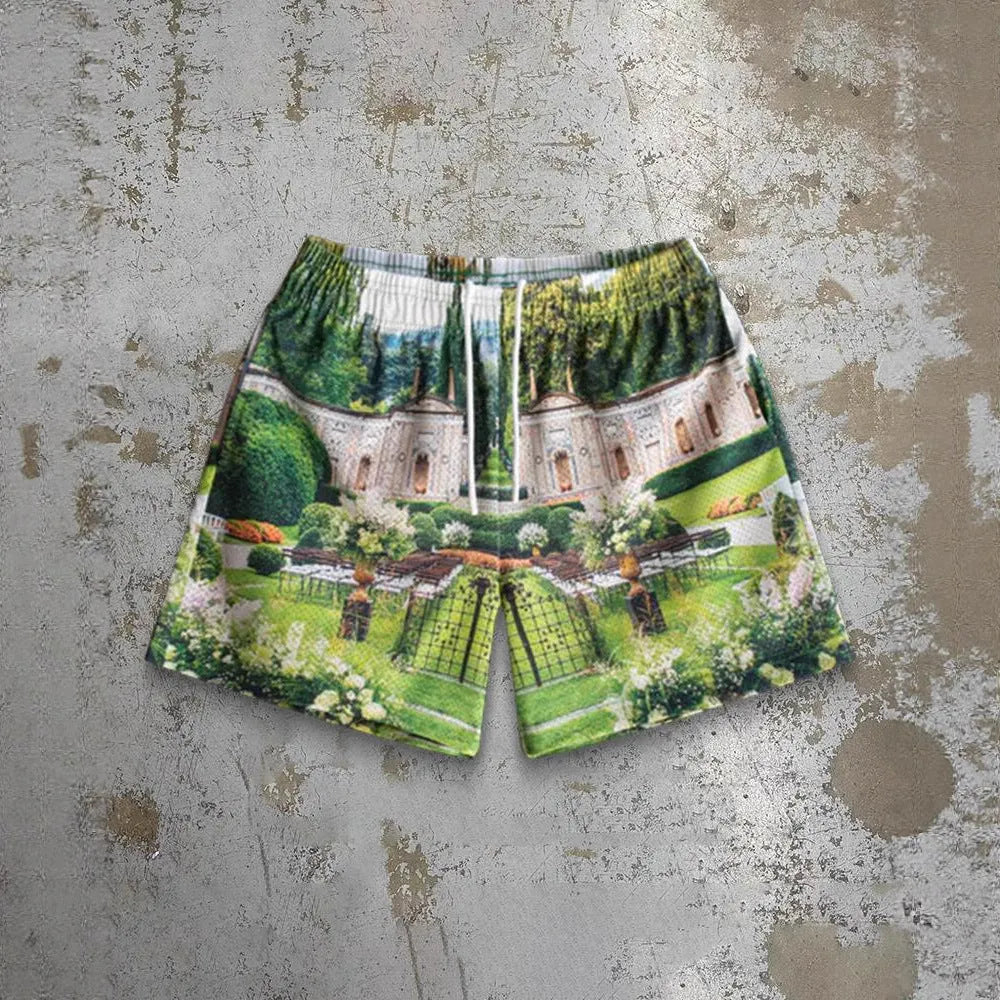 Man's loose blue digital print beach shorts with elastic waistband on a sandy background.