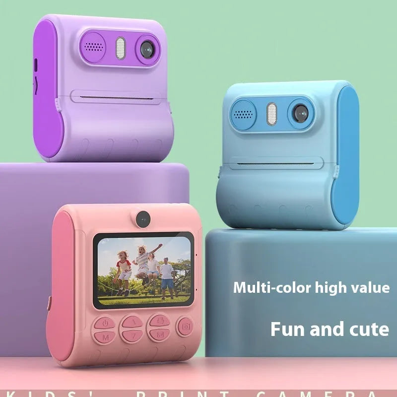 Children's instant thermal printing camera in pink with dual lenses, including lanyard and charging cable on white background