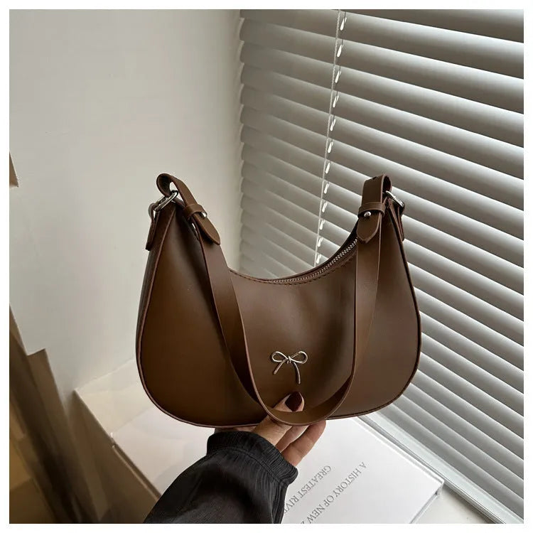 Small dumpling-shaped PU leather shoulder bag for women in multiple colours, showing the single strap and external pocket