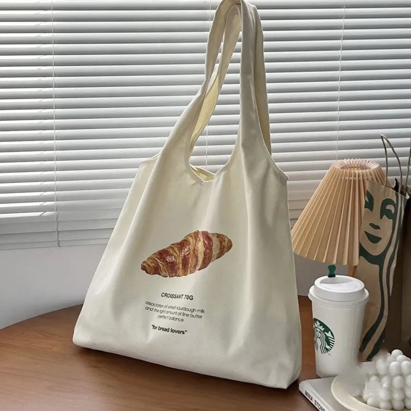 Beige canvas one-shoulder tote bag with printed bread and croissant designs