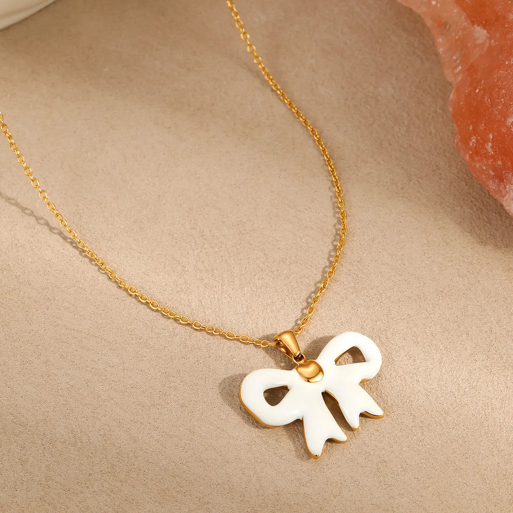 18K gold plated stainless steel bowknot necklace with adjustable chain and matching stud earrings on white background