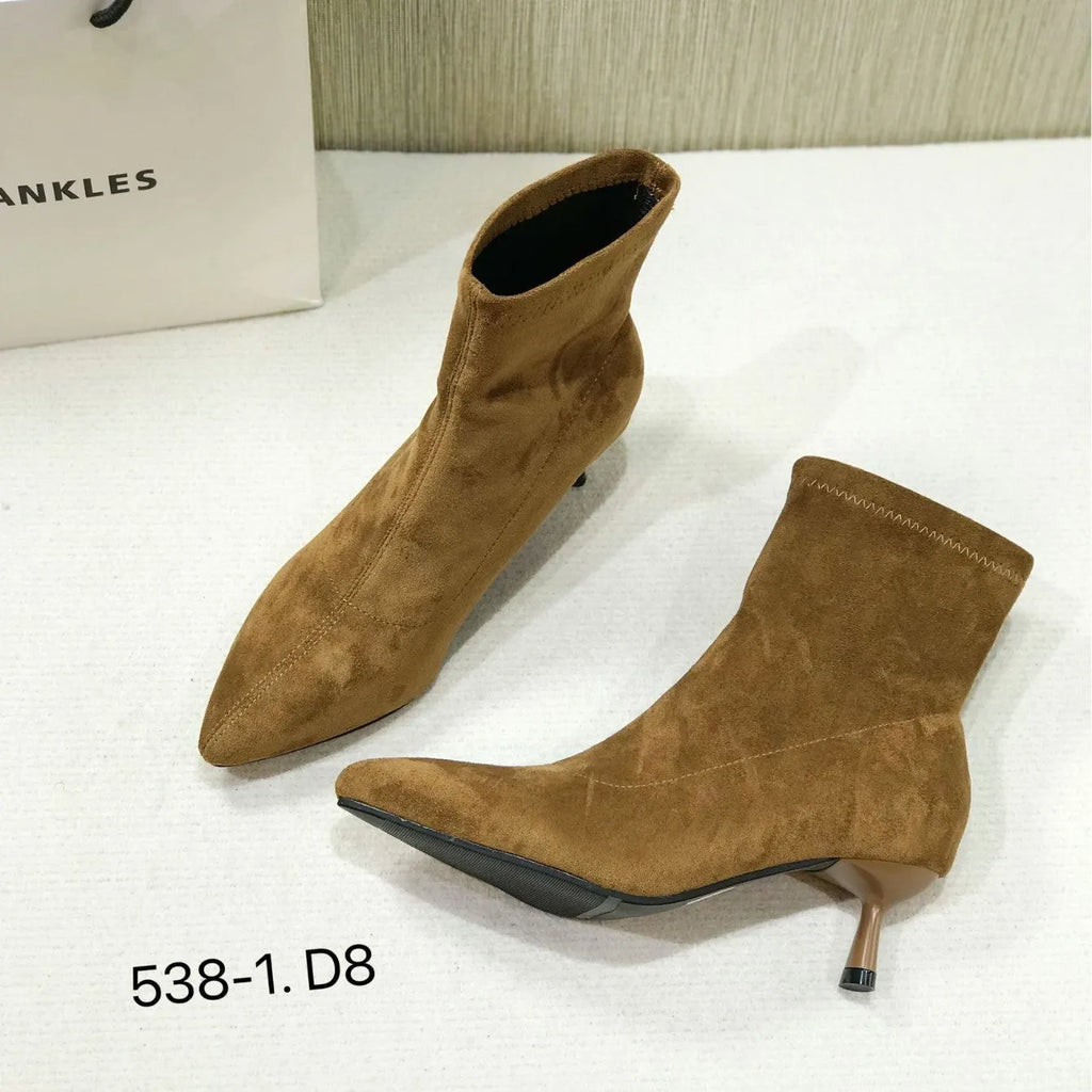 Black microfiber ankle boots with a stiletto heel and pointed toe on a mid-calf sock.