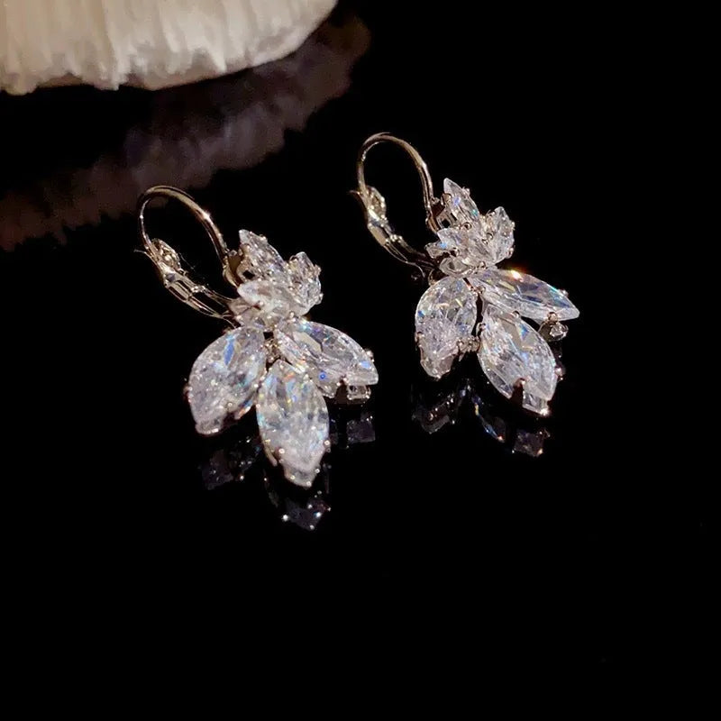 Platinum colour leaf-shaped earrings with inlaid zircon stones on white background