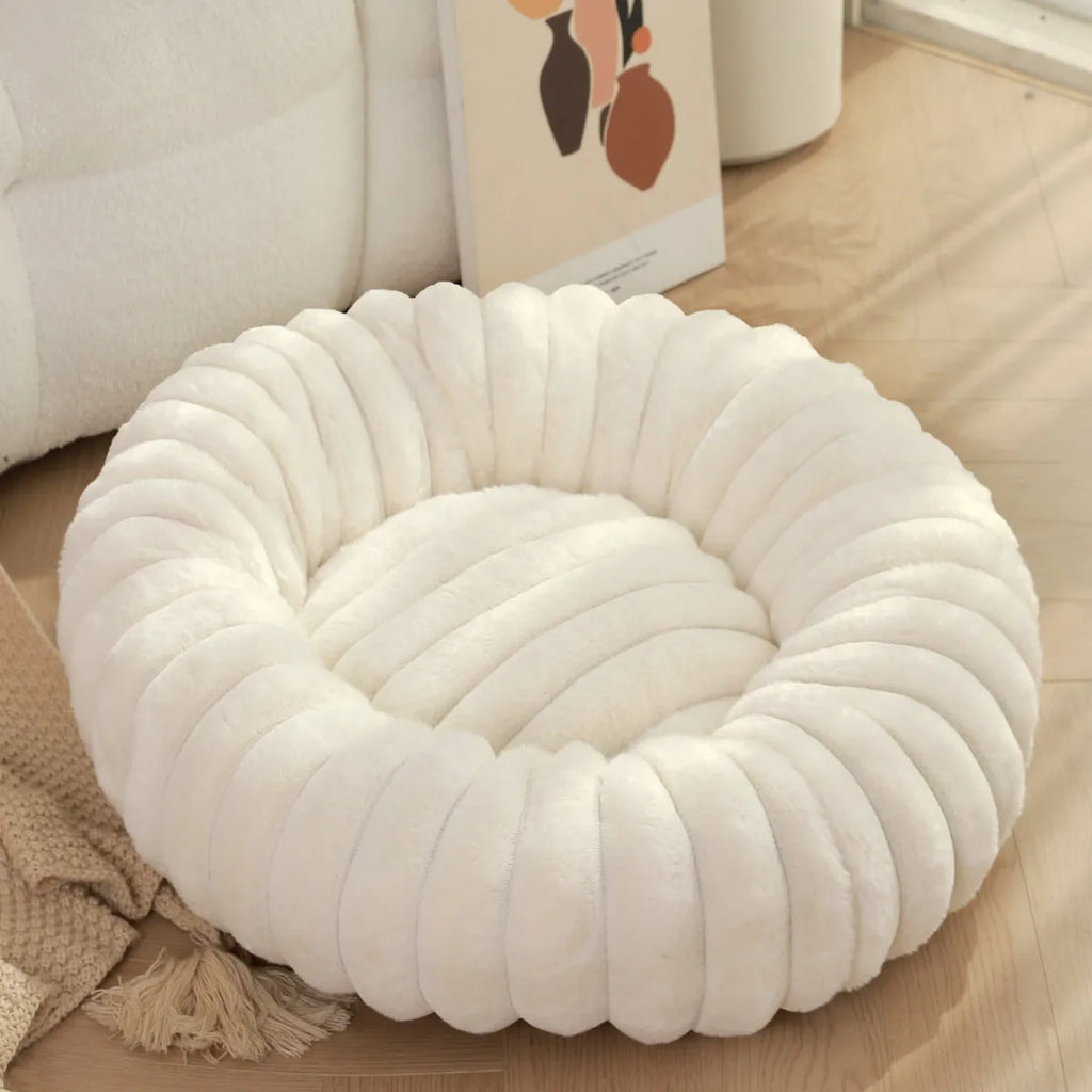 Round beige plush pet bed mat for dog or cat on wooden floor